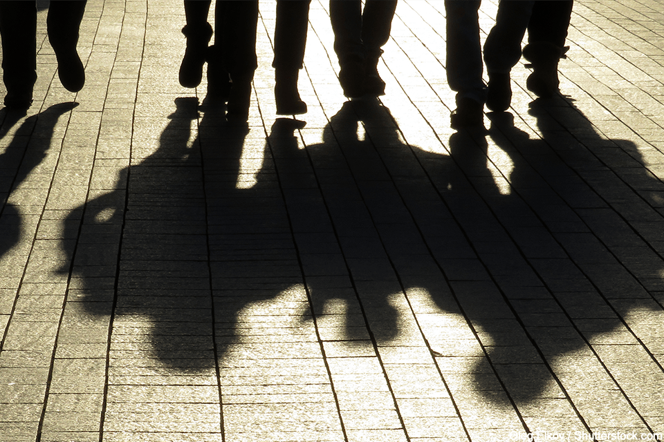 People's legs in the background, with their shadows in the foreground