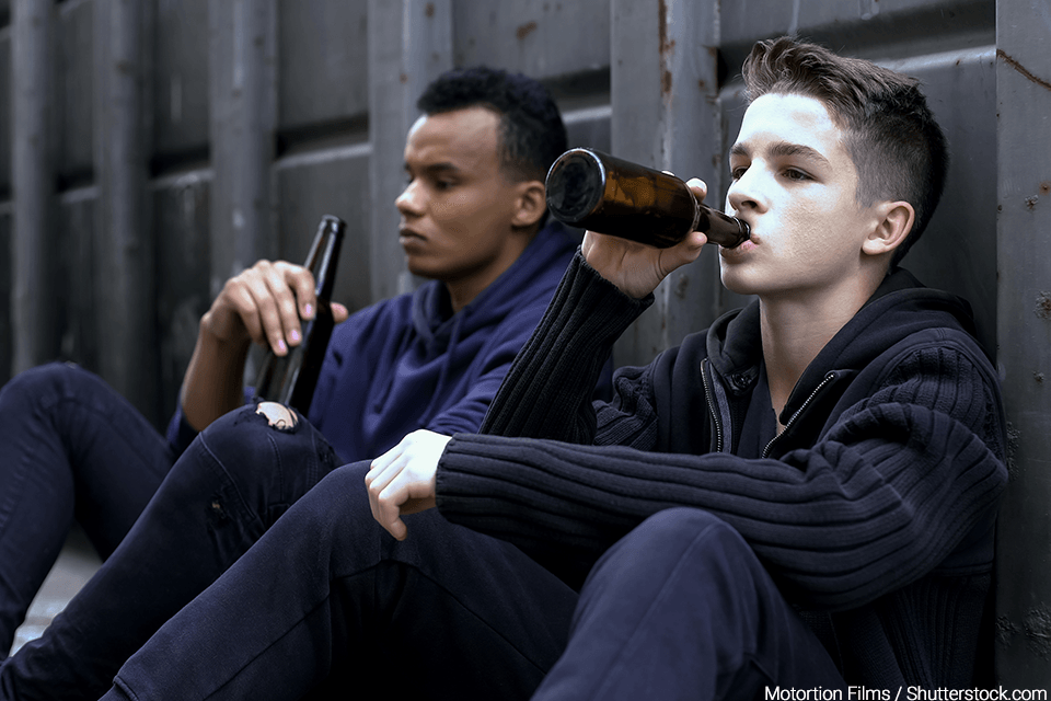 Two teenagers in an alley drinking beer together