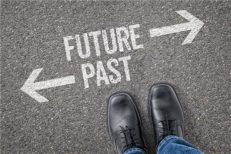 A person standing with their shoes near the words "FUTURE" and "PAST" painted on the concrete with arrows pointing in different directions.