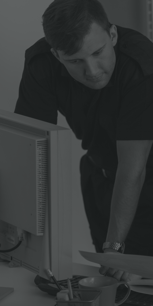 a man bending down to look at a computer monitor on a desk