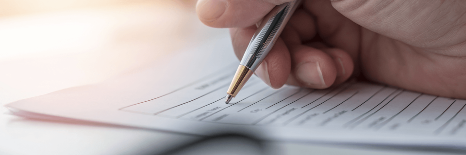 Hand holding a pen, filling out a form