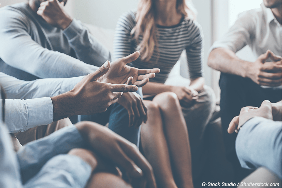 Group of people sitting in circle discussing something
