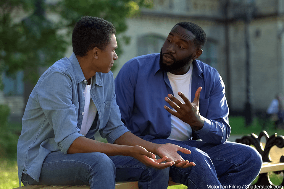 A father talking to his son on a park bench