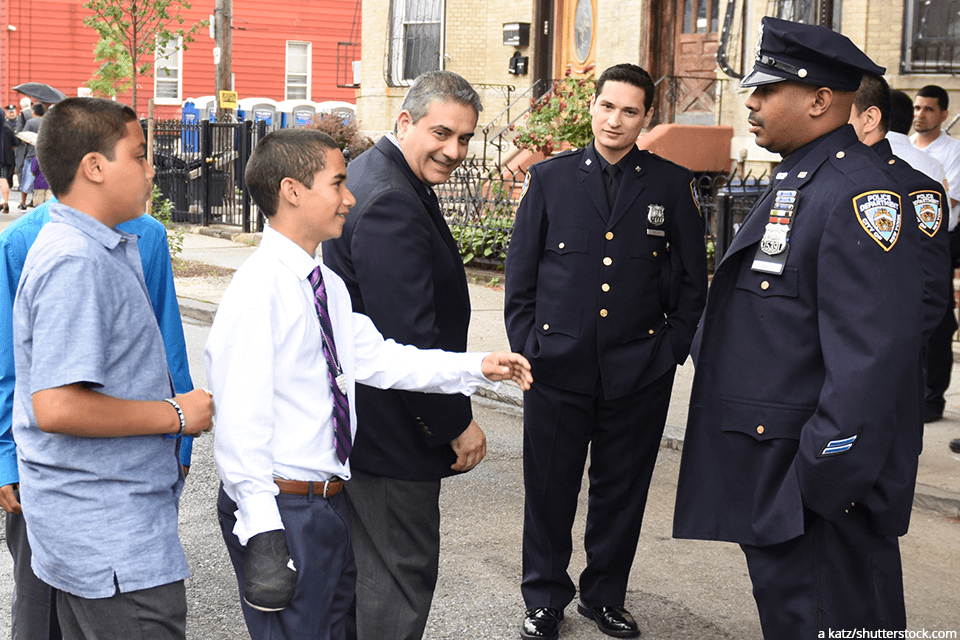 a young man reaching out to shake a police officers hand
